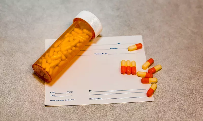 Tablets spilling from an amber bottle onto a prescription pad